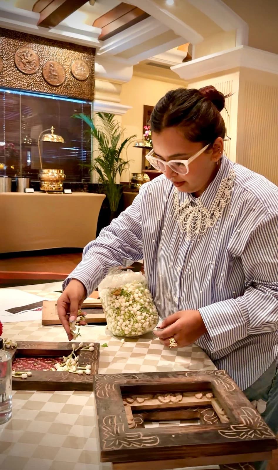 Aishwarya arranging jasmine buds by hand on decorative wooden trays