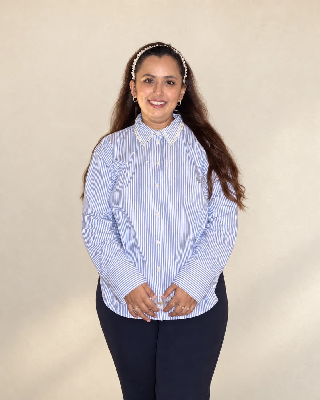 Aishwarya Luthra smiling, wearing a pearl-trimmed striped shirt